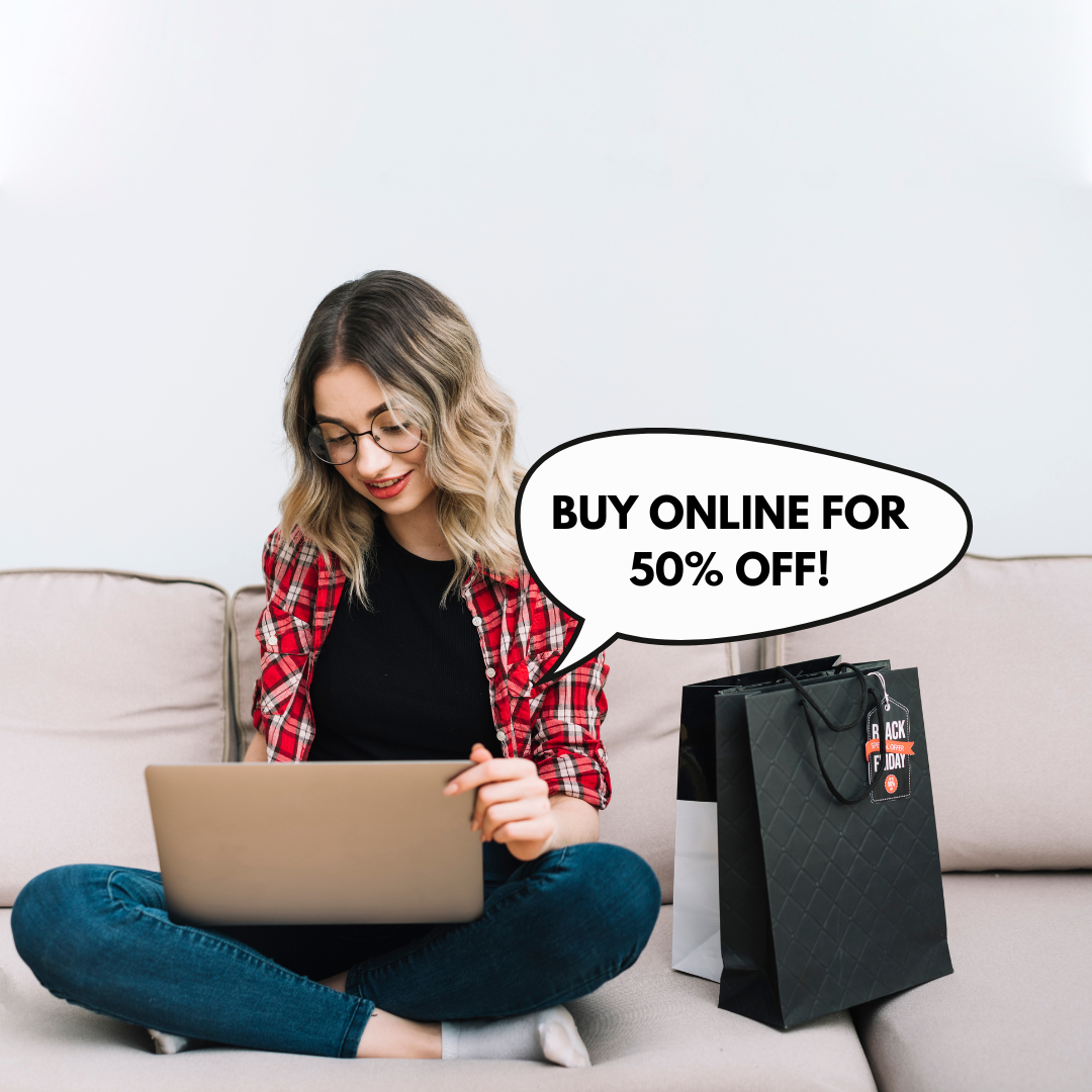 Blonde girl in red flannel sitting on a couch next to shopping bags, using her laptop.