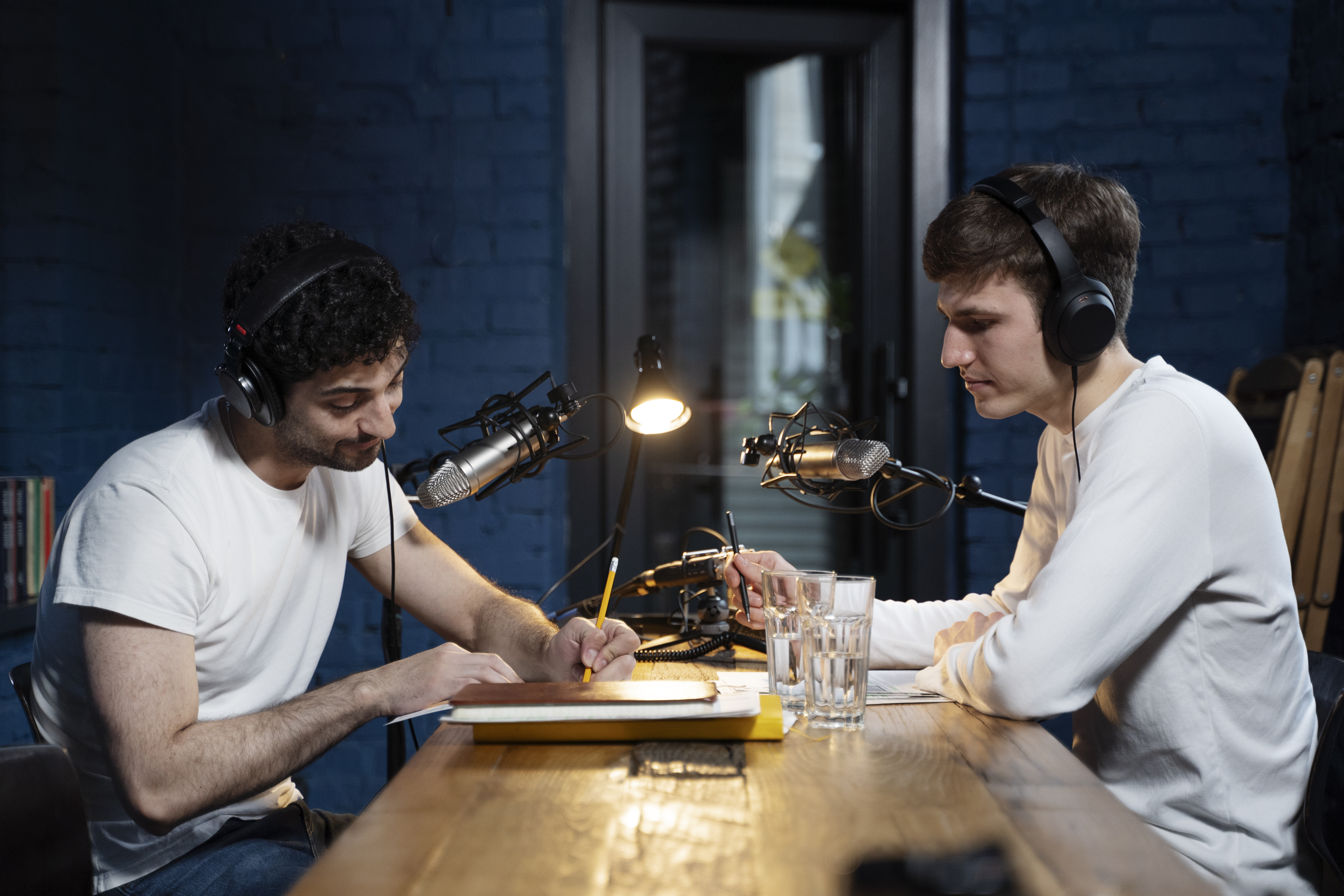 Two podcast hosts recording an episode together, using microphones and headphones in a studio setting.